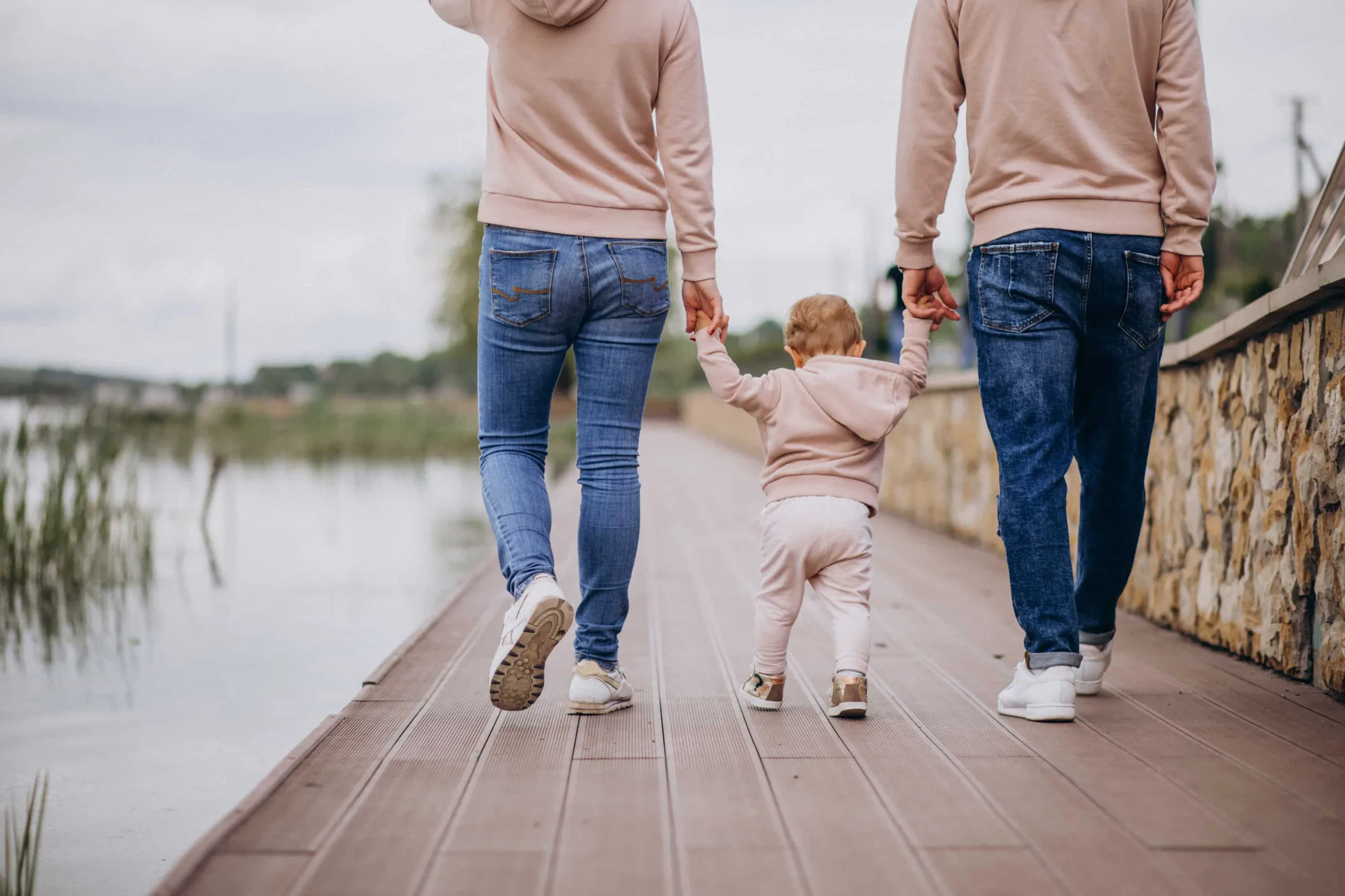 Familj som går hand i hand tillsammans med en liten unge.